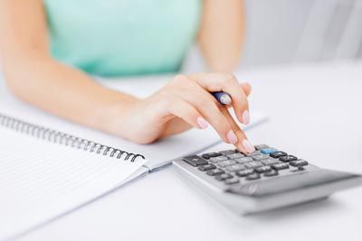 woman using a calculator while taking notes