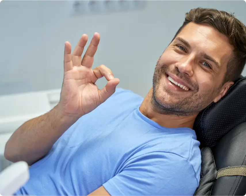 Man relaxed in dental chair giving okay sign