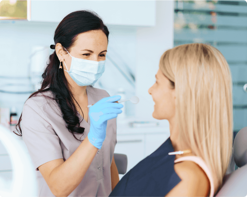 Smiling female patient in dental chair for checkup with female dentist