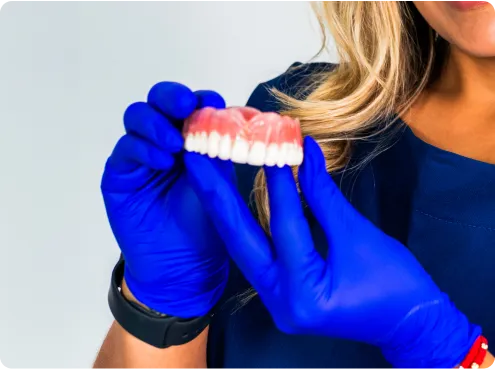 Close-up photo of a person wearing blue gloves holding a dental denture