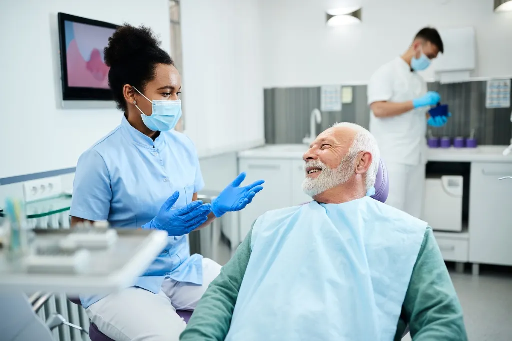 Relaxed senior man smiles reassuringly at dentist before dental treatment.