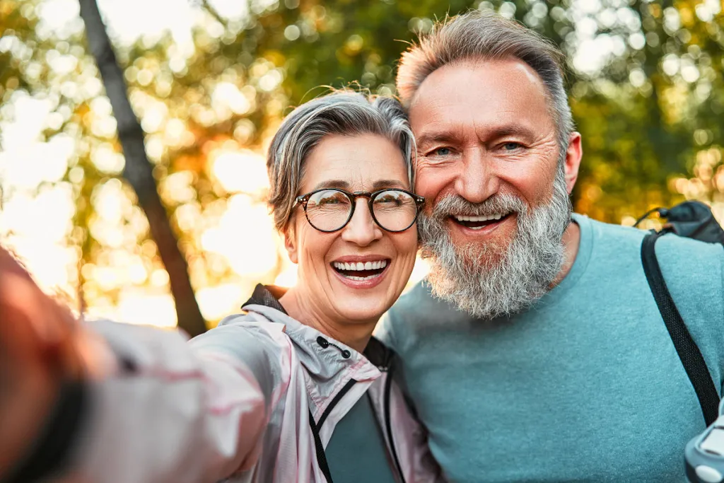 Playful senior couple captures a joyful selfie, radiating happiness with bright smiles.