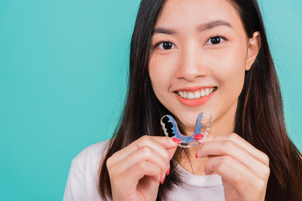 Teeth retaining tools after removable braces, Portrait young Asian beautiful woman smiling holding silicone orthodontic retainers for teeth, Orthodontics dental healthy care concept