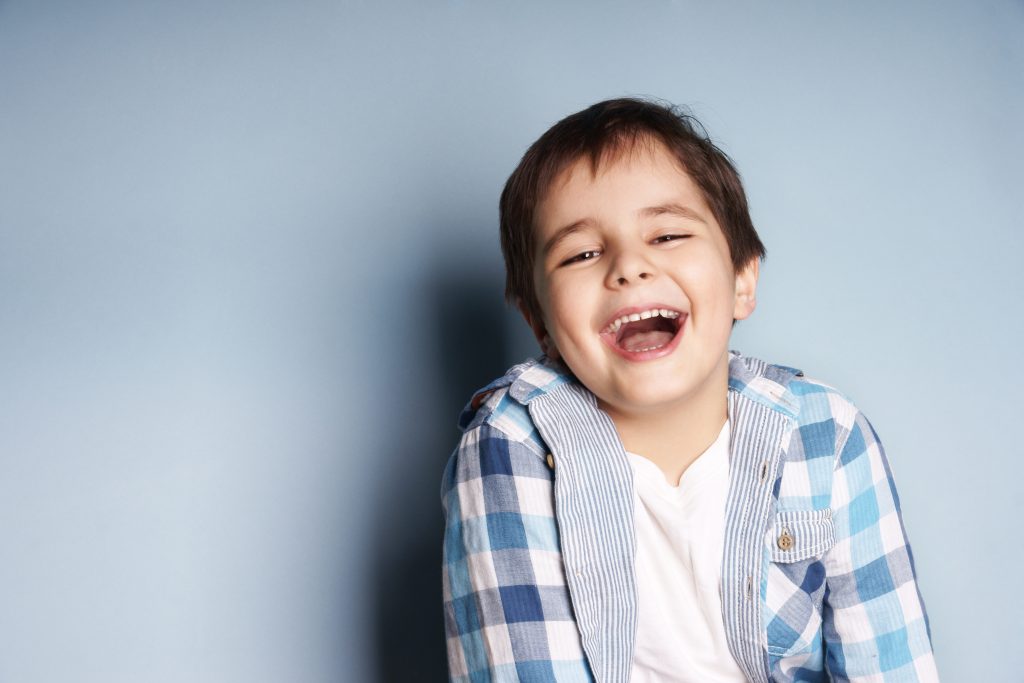 Boy laughs heartily, revealing his bright white teeth in a contagious display of joy.