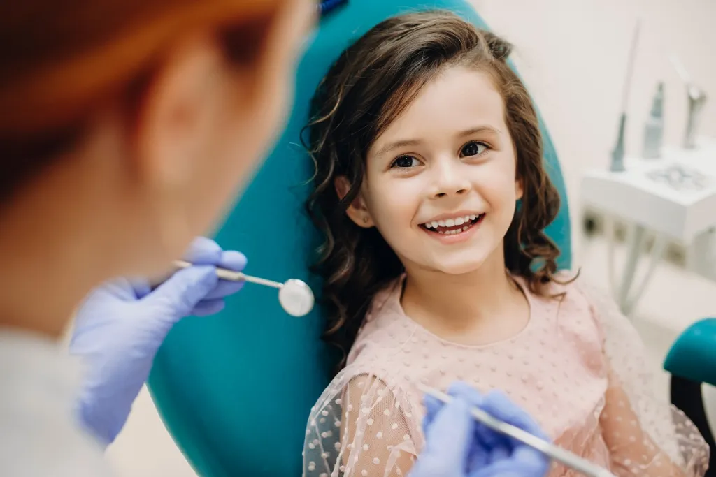 Young girl smiles confidently at dentist during a happy dental checkup.