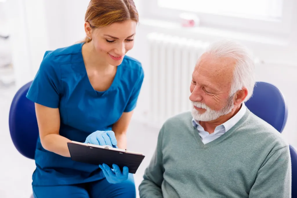 Smiling senior man listens attentively as dentist explains treatment options.