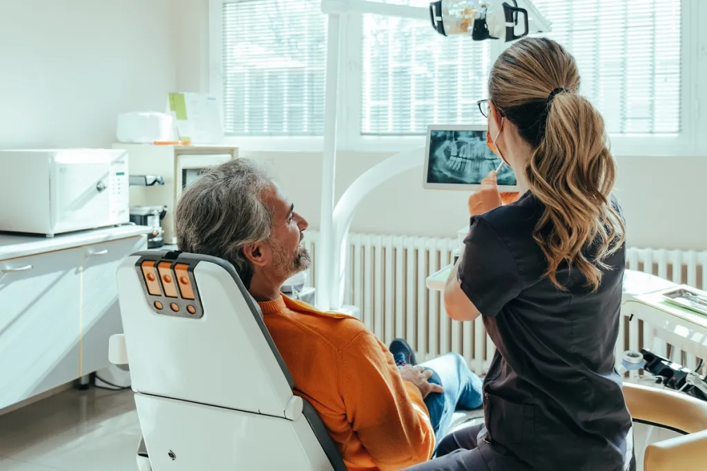 Attentive senior man listens to dentist explain dental X-ray.
