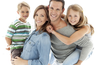 Confident family portrait: Mom, dad, and two children all smiling brightly with healthy teeth