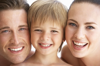Happy family of three: Mom, dad, and child smiling brightly, showing off healthy teeth