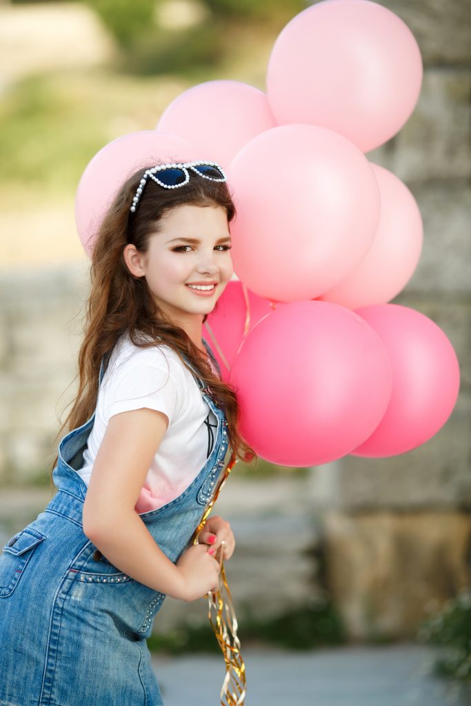 Smiling young woman with colorful balloons, showing off bright white teeth