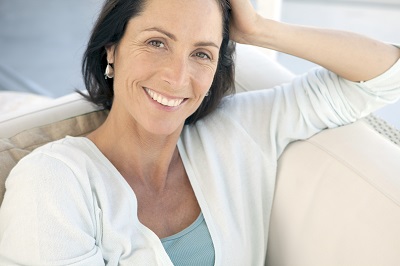 Confident middle-aged woman with hand on head, smiling brightly