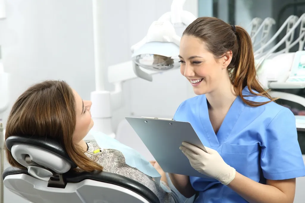 Smiling female dentist consulting with relaxed patient in reclining dental chair